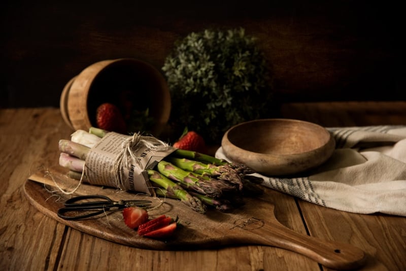 Vegetables, herbs and wooden bowls on a rustic kitchen surface