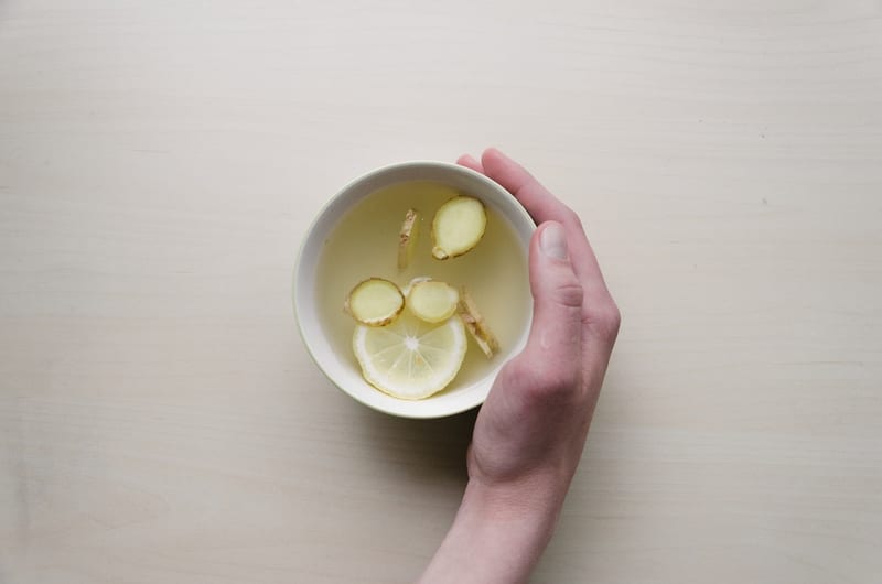 A hand holding a cup of lemon tea
