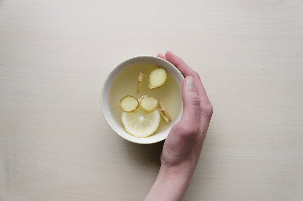 A hand holding a cup of lemon tea