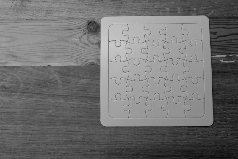 An unpainted wooden jigsaw puzzle on a wooden table