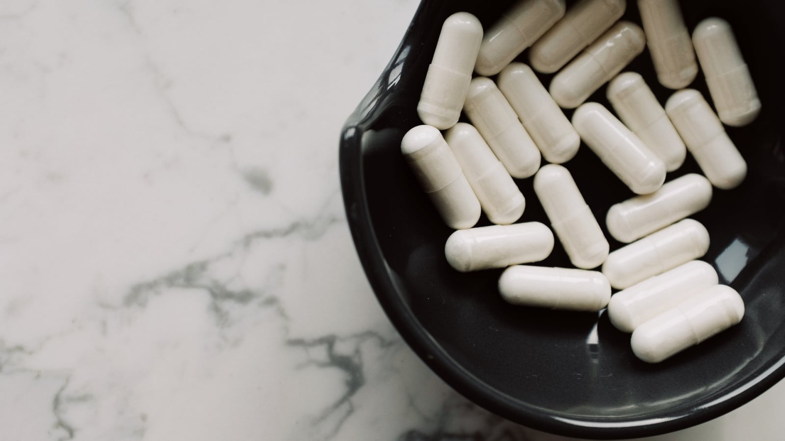 White capsules in a dark bowl