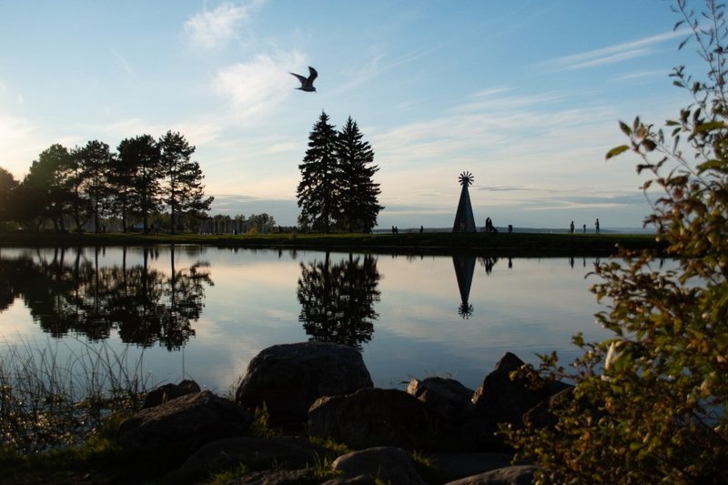 Trees and a waterfront structure reflected in still water at sunset