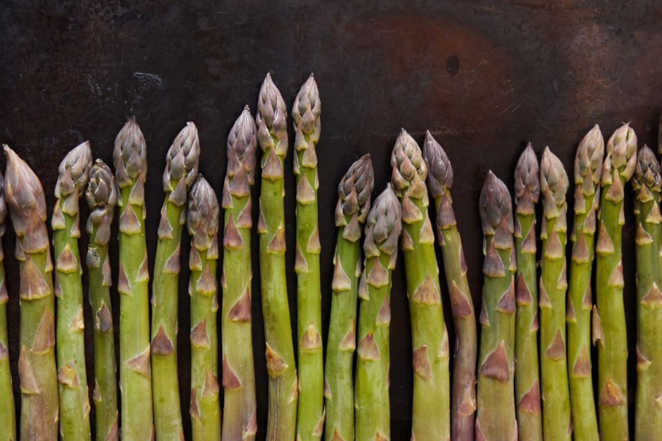 Fresh asparagus spears arranged on a dark surface