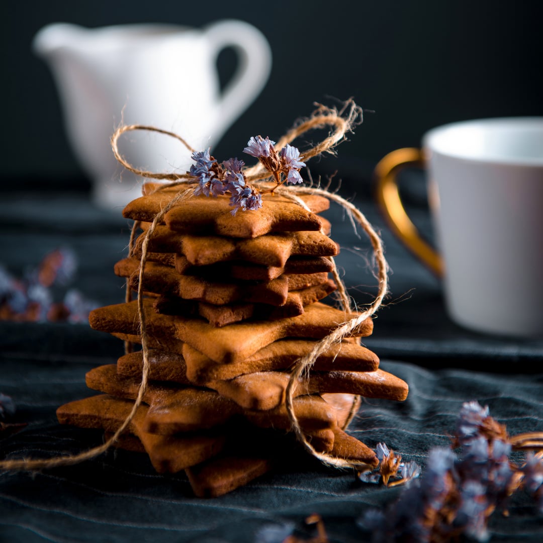 A stack of gingerbread cookies beside cups