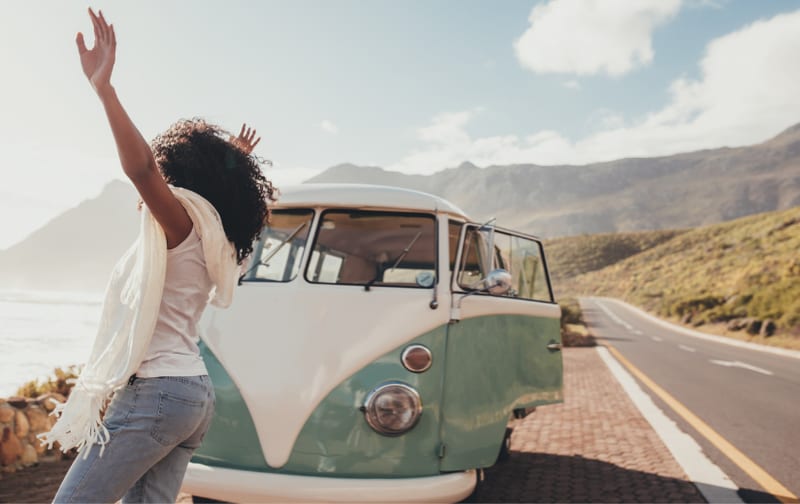 A person leaning out of a camper van on an open road