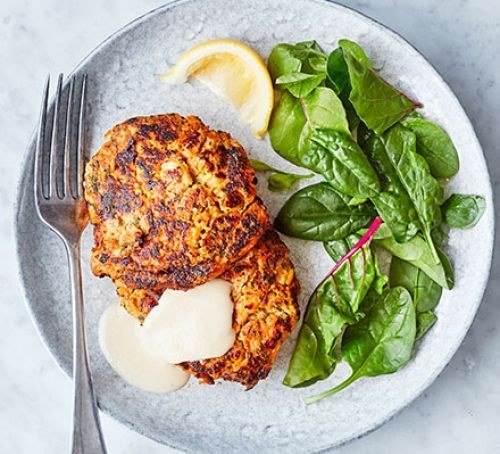 Golden fishcakes with leafy greens, lemon and dressing on a plate