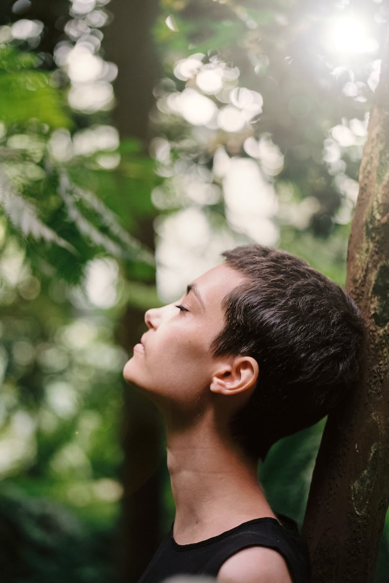 A woman standing beneath leafy branches