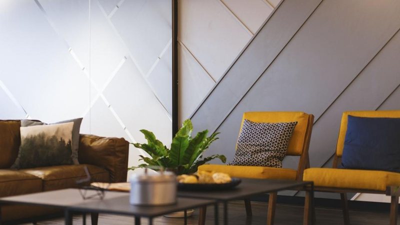 Yellow armchairs, a sofa and a potted fern in a softly lit sitting area