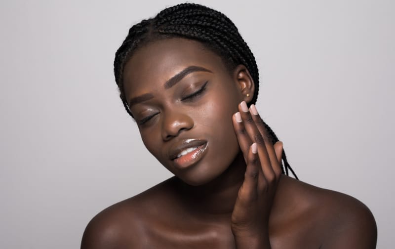 A woman gently touching her cheek