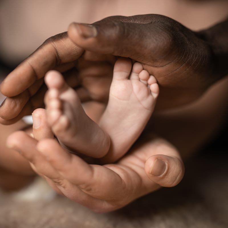 An adult hand gently holding a baby's feet