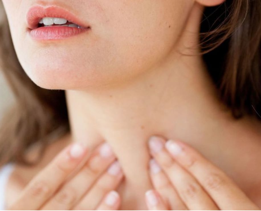 A woman resting her hands against her neck