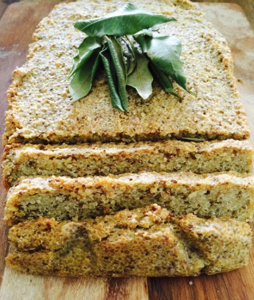 Sliced seeded loaf on a wooden board, topped with green leaves