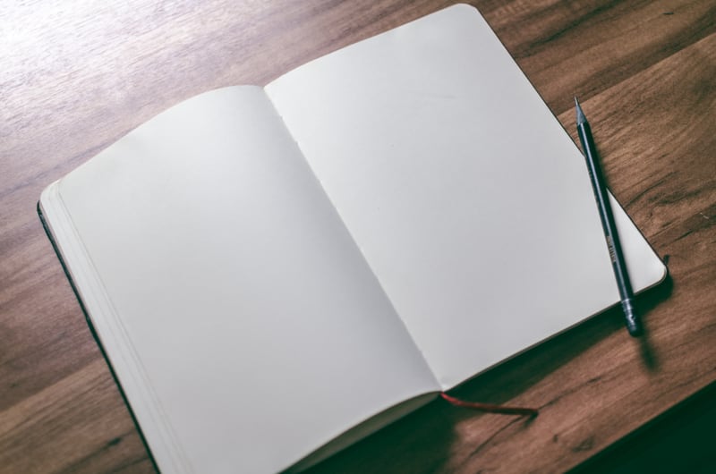 An open blank notebook and pen on a wooden table