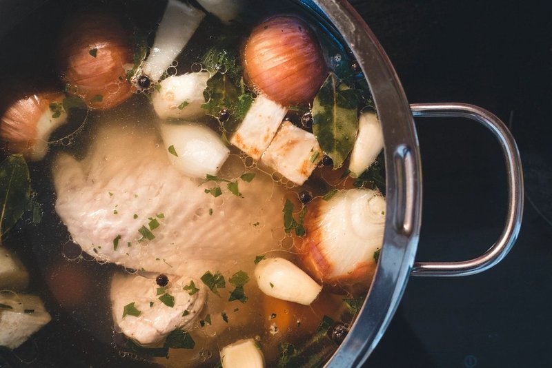 Chicken, onions, garlic and herbs simmering in a pot of broth