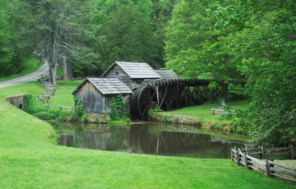 An old wooden watermill beside a quiet green pond