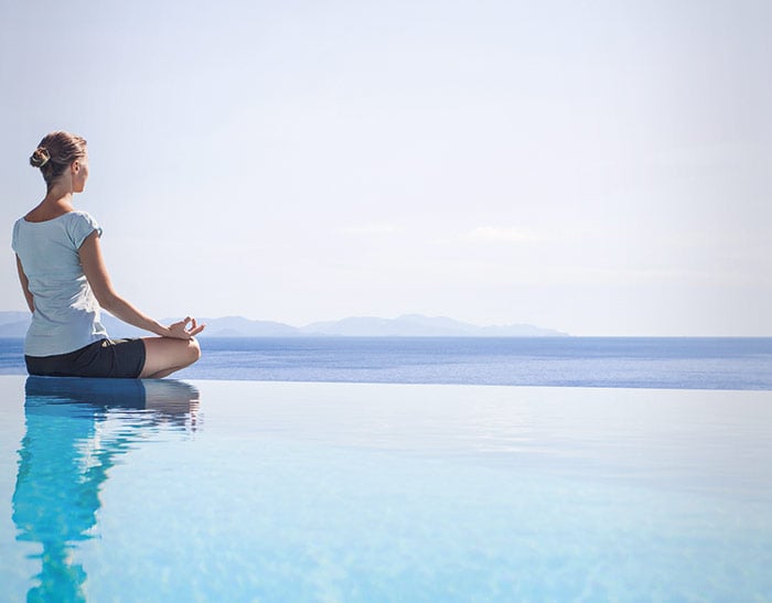 A person meditating beside water