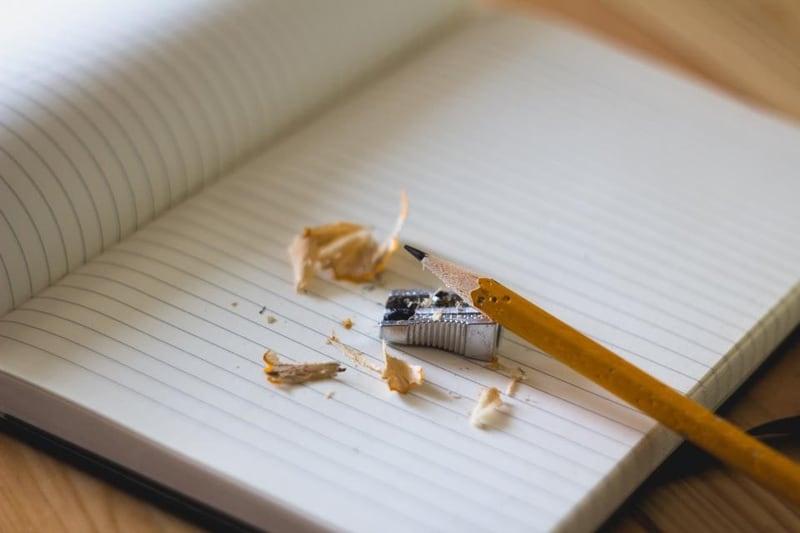 A pencil, sharpener and shavings on an open lined notebook