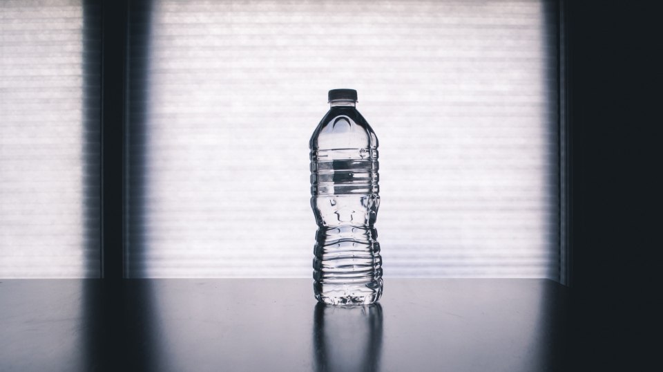 An unlabelled bottle of water on a table in soft window light