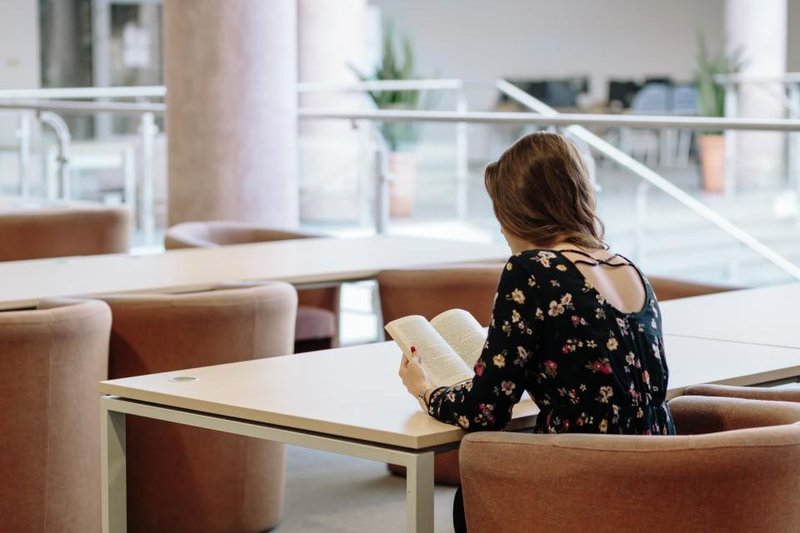 A person seen from behind reading a book at a cafe table