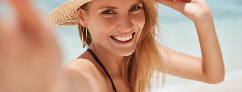 A smiling woman wearing a sun hat