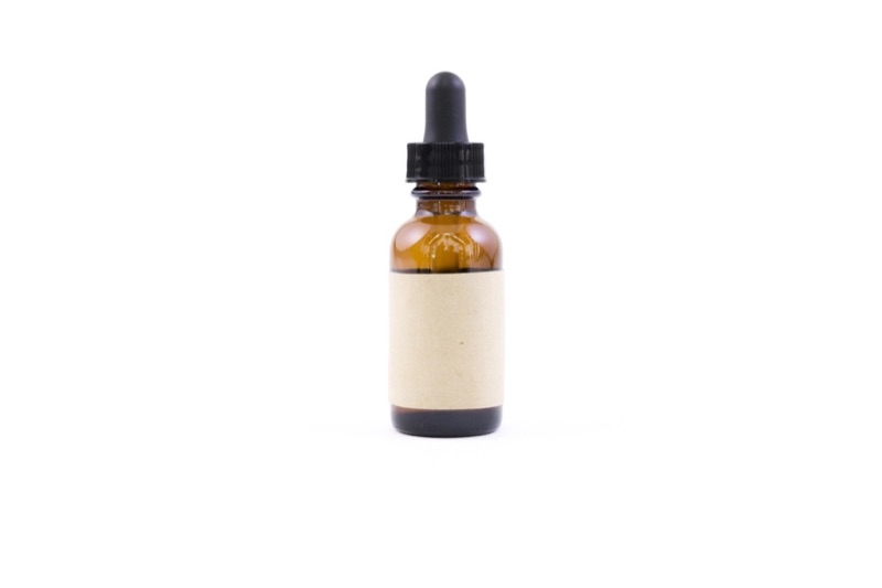 An amber glass dropper bottle with a blank paper label on a white background