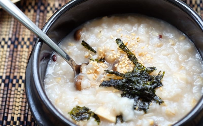A bowl of chicken congee with herbs and seeds