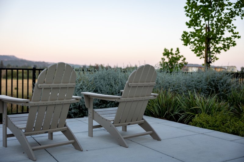 Two empty chairs on a terrace beside a garden